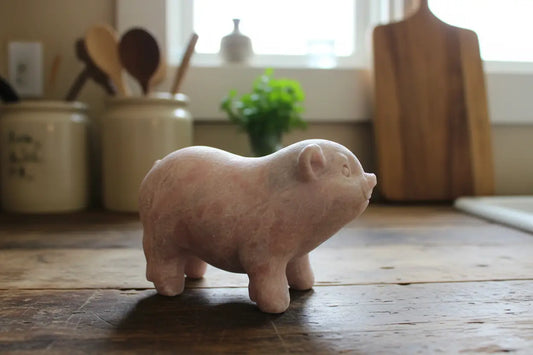 A pink calcite figurine of a pig made from actual crystal, standing on a country kichen counter 