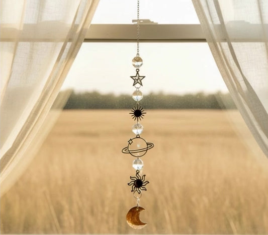 Suncatcher in a window open curtains with a hay field behind breeze blowing the suncatcher