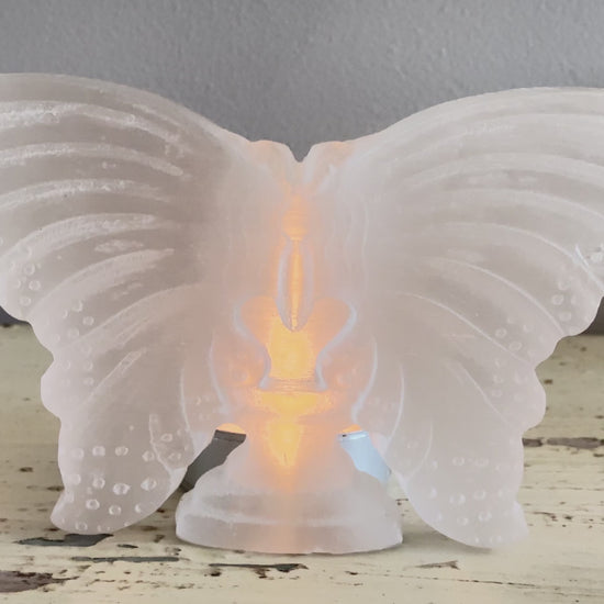 Carved satin spar butterfly with a tea candle behind it 