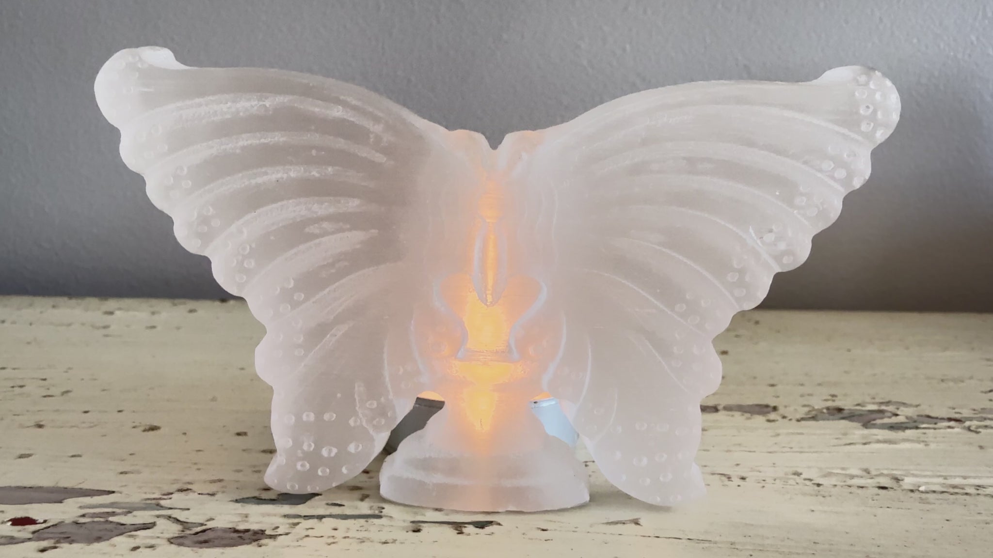 Carved satin spar butterfly with a tea candle behind it 