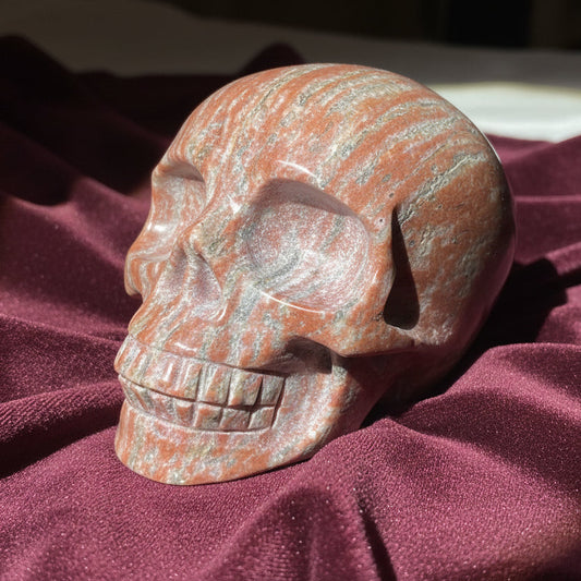 Brecciated Jasper hand carved human skull. bright copper and off white with streaks of hematite and iron oxide 