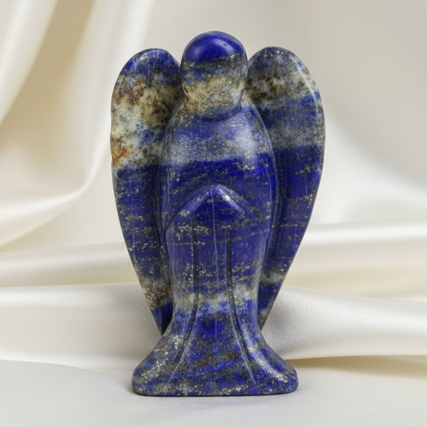 A small carved stone angel figurine with blue and white lapis lazuli- photographed against  an off white fabric