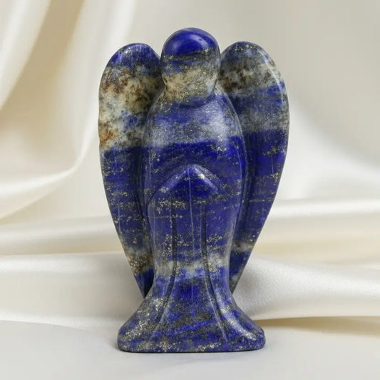 A small carved stone angel figurine with blue and white lapis lazuli- photographed against  an off white fabric