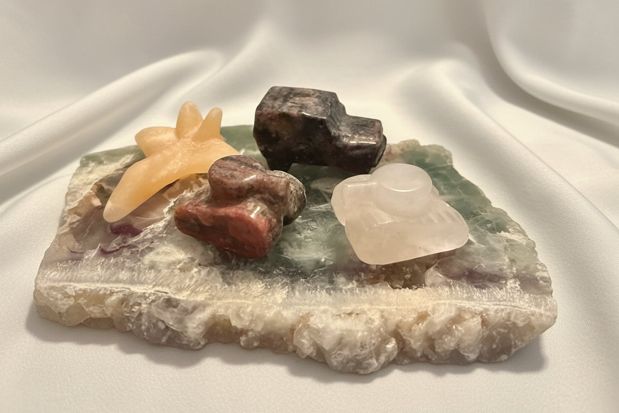 photo of four hand carved pieces, two tanks, clear quartz with citrine inclusion, brecciated jasper, yellow calcite jet, and yooperlite jeep truck  