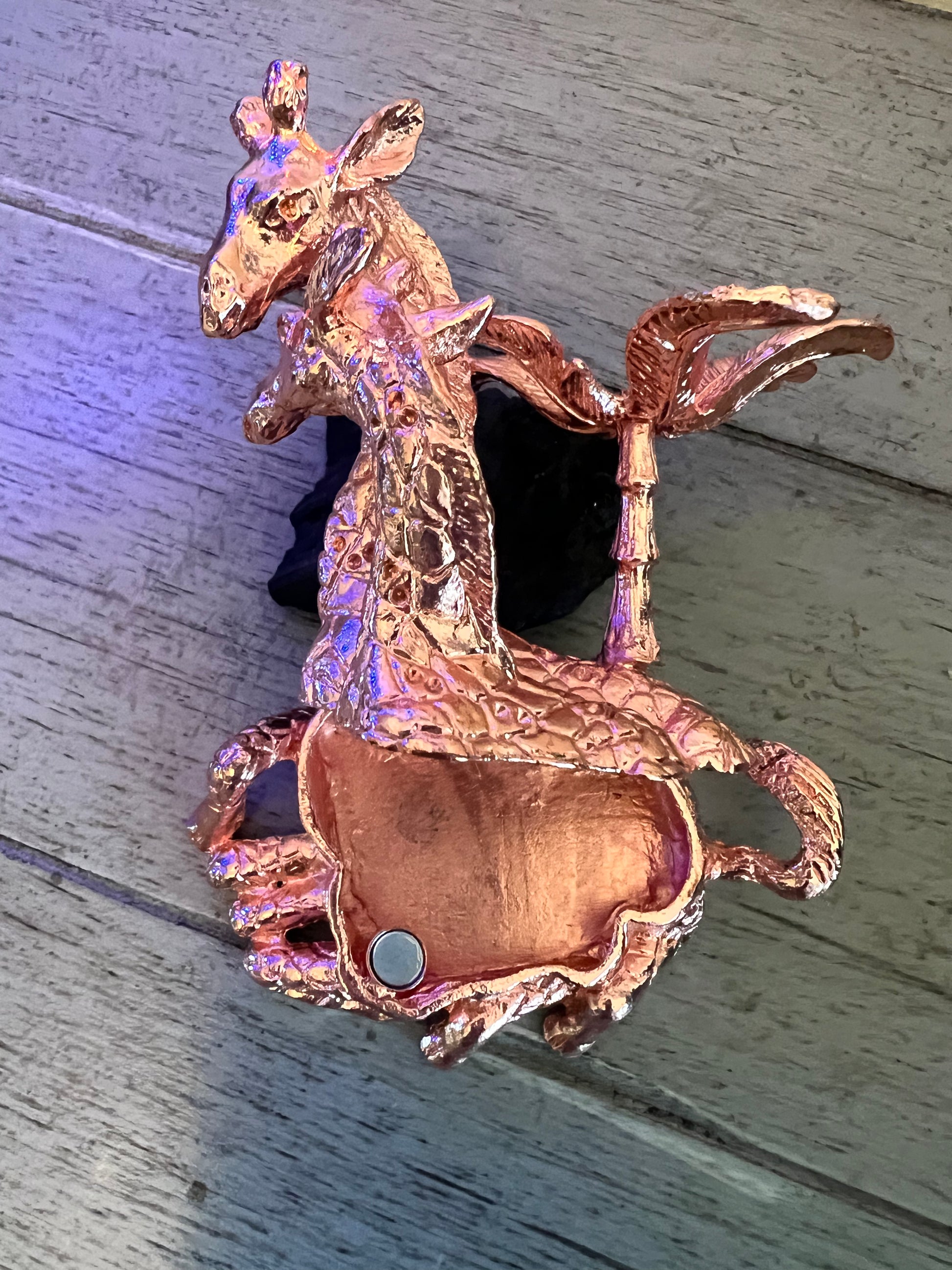 Copper-colored giraffe figure with palm tree.