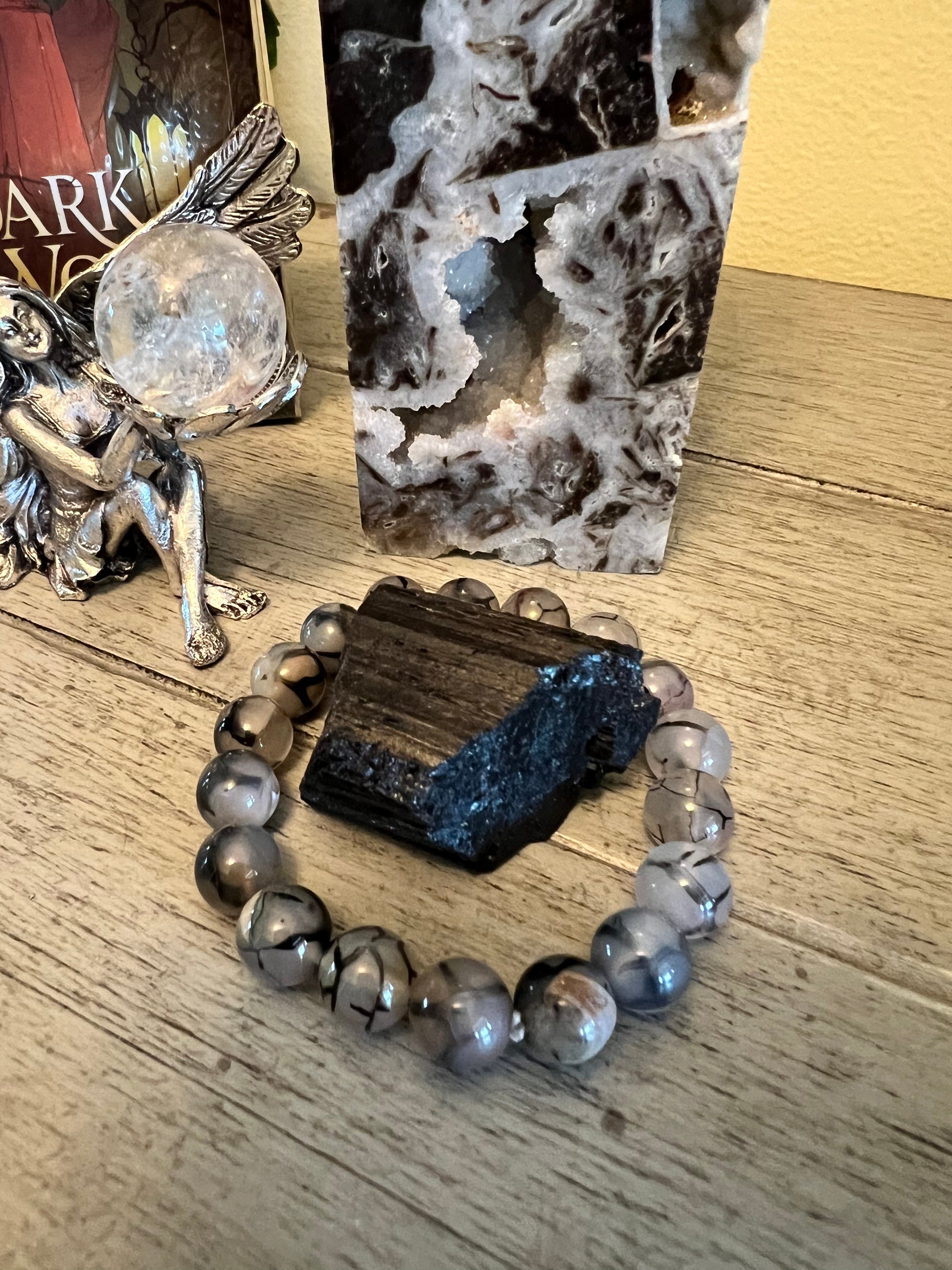 Close-up of crystals, a beaded bracelet, and a fairy figurine on a wooden surface.