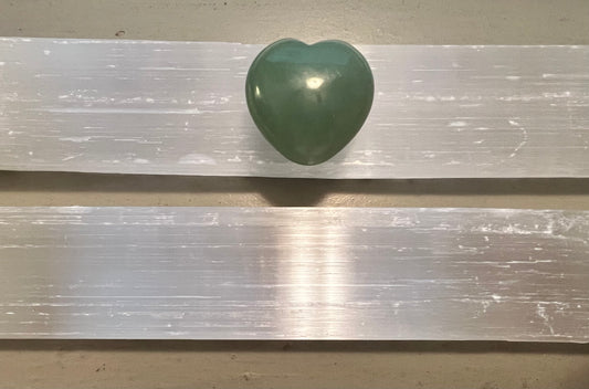 Green heart-shaped stone on two selenite crystals.