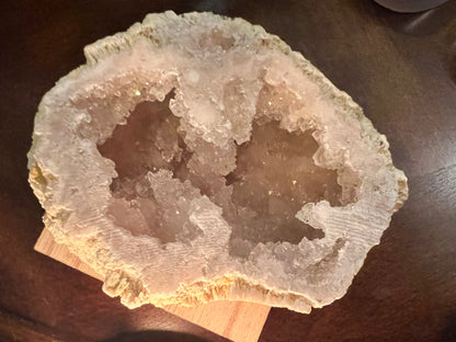 Geode with crystalline interior, displayed on a wooden surface.
