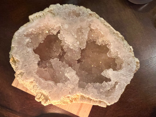 Geode with crystalline interior, displayed on a wooden surface.
