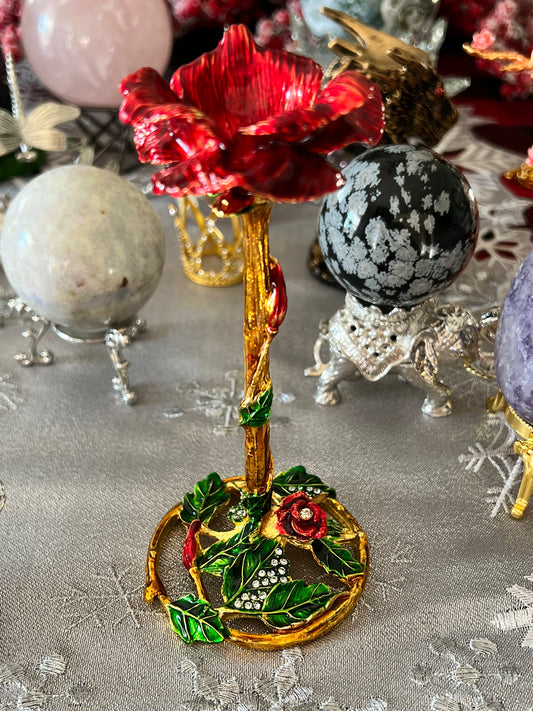 Close-up of a decorative red rose jewelry box with gold and green accents, surrounded by crystal spheres on embellished stands.
