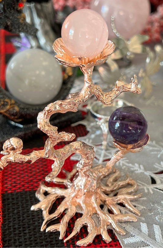 Metal tree sculpture holding rose quartz and amethyst spheres.