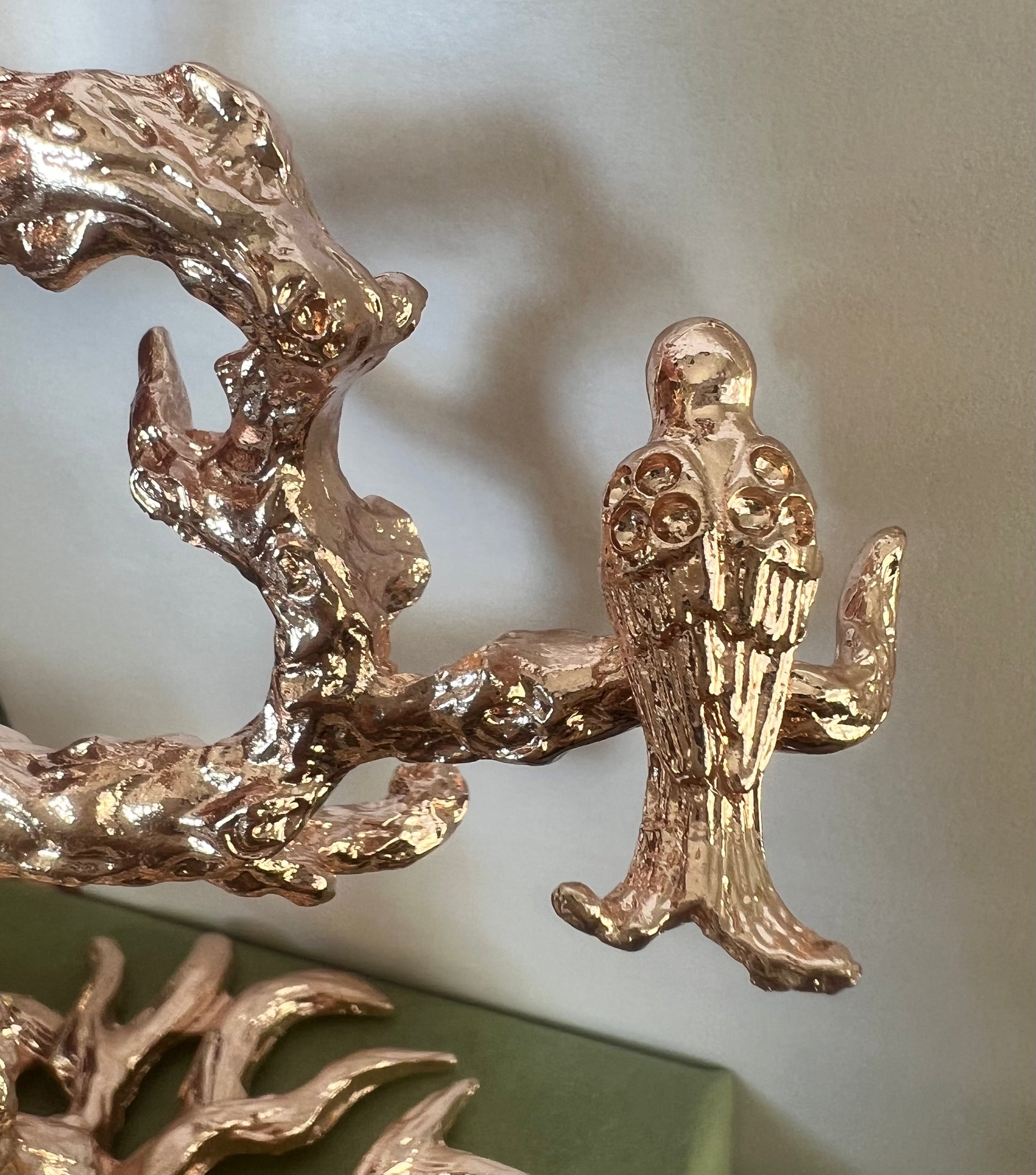 Gold bird figurine perched on a gold branch.