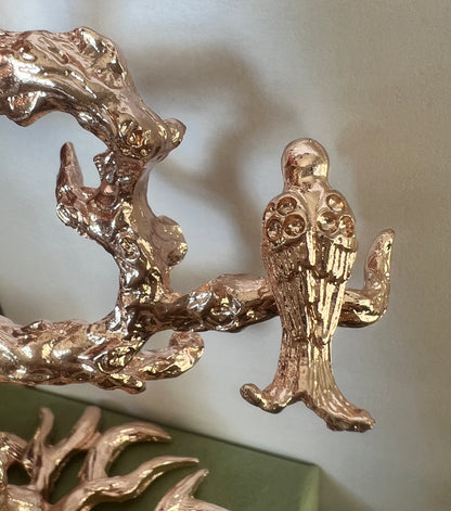 Gold bird figurine perched on a gold branch.