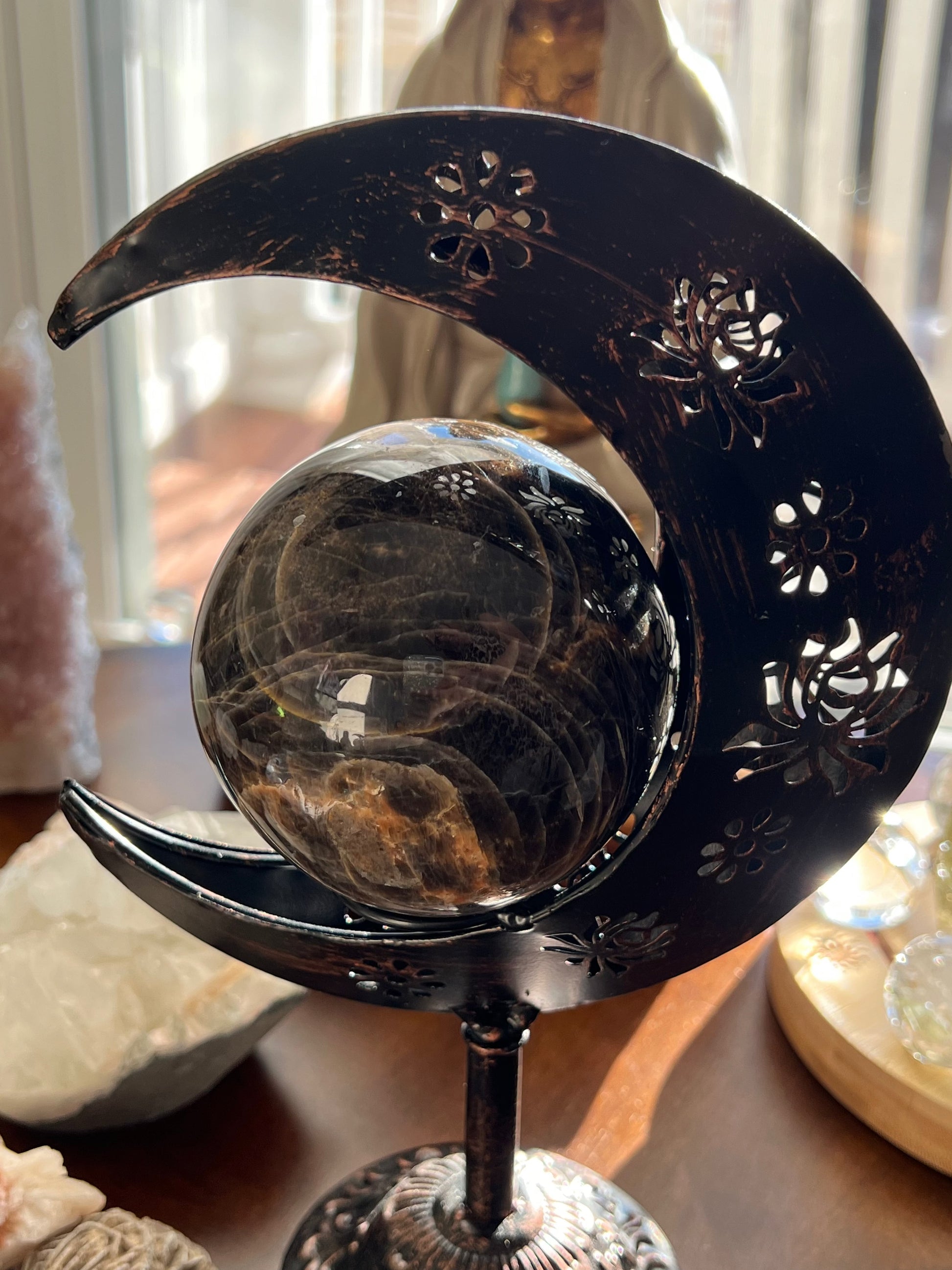 Smoky crystal ball held by decorative metal crescent moon stand.