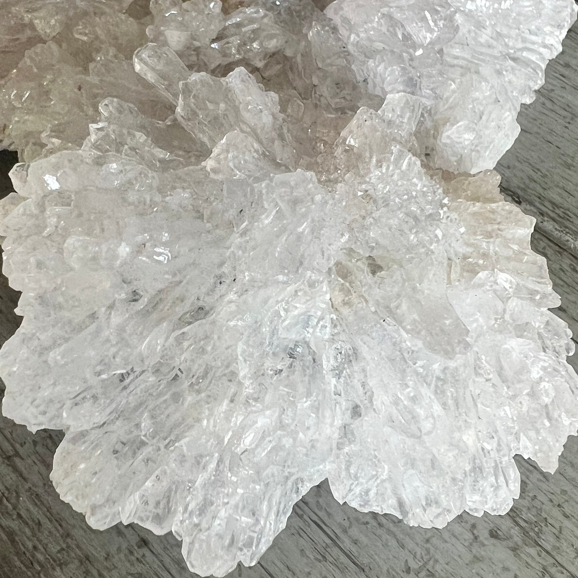 A large, crystalline cluster on a wood-grain surface.