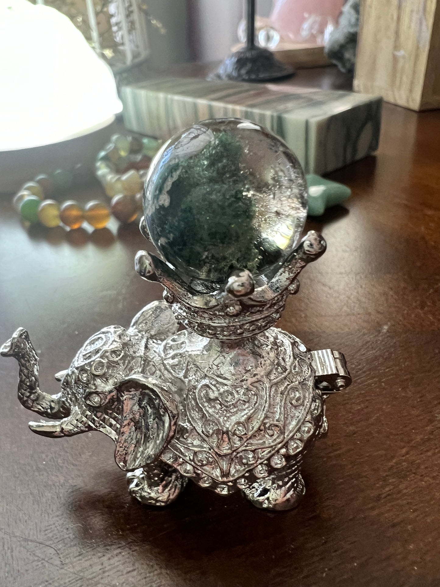 Silver elephant figurine holding a crystal ball.
