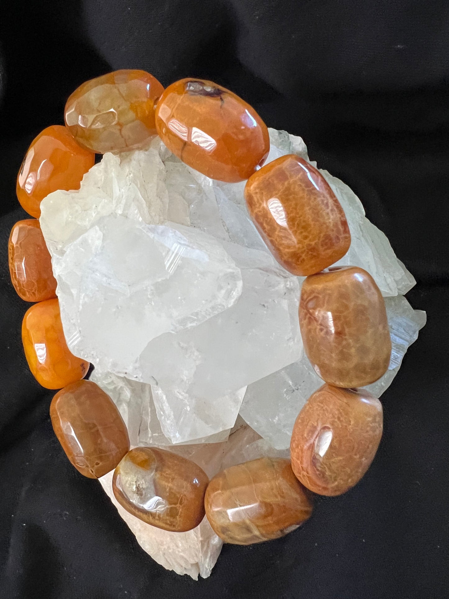 Close-up of orange stones arranged on white crystals against a black background.
