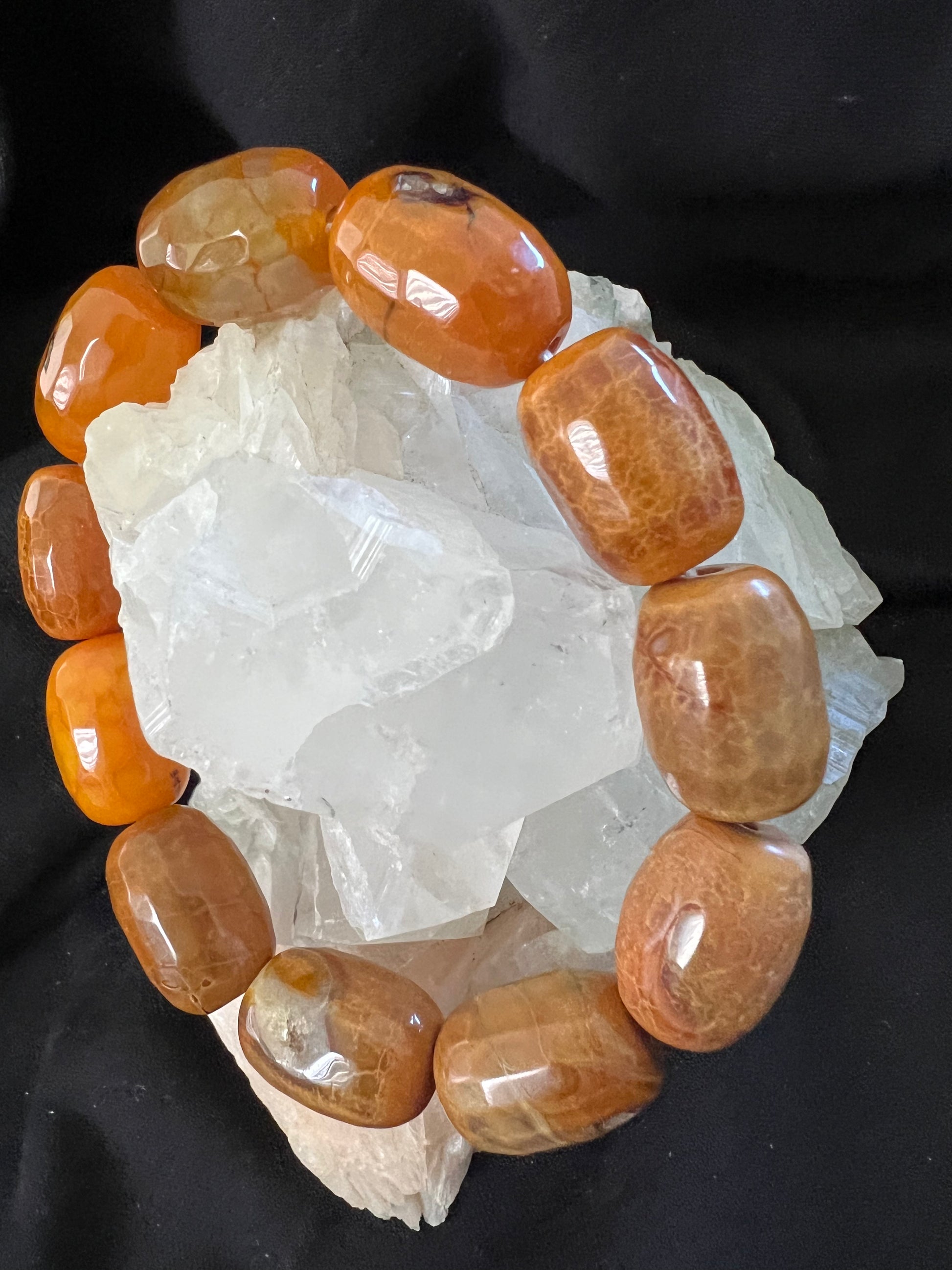 Close-up of orange stones arranged on white crystals against a black background.
