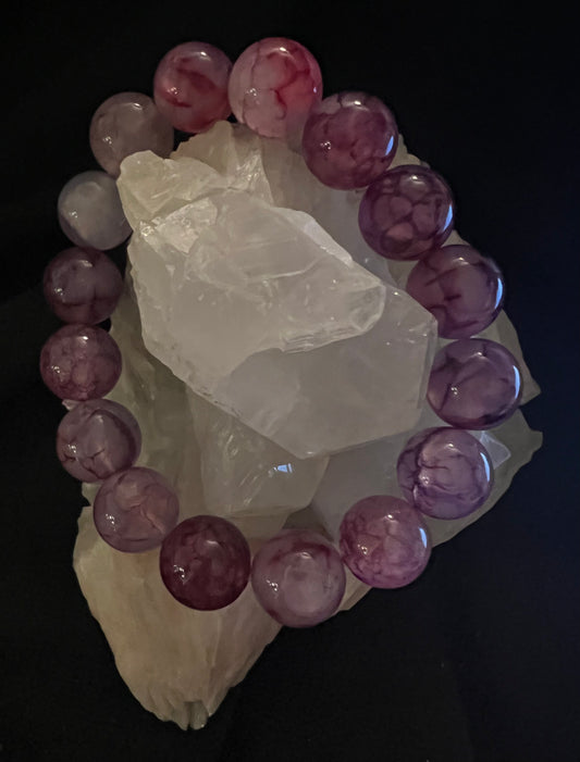 Purple beaded bracelet encircling a cluster of clear crystals on a black background.