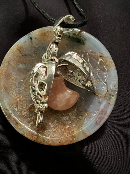 Round agate pendant with a silver locket and a peach moonstone on a black cord.