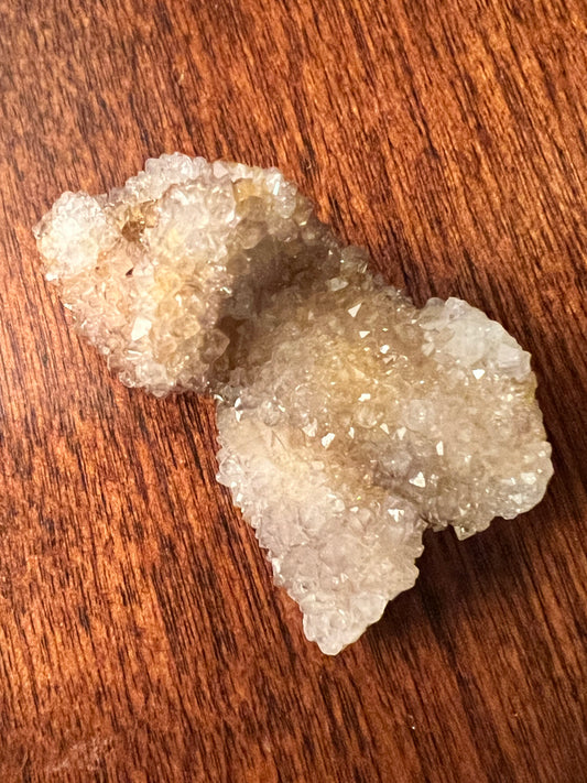 Sparkly quartz crystal on wood grain.