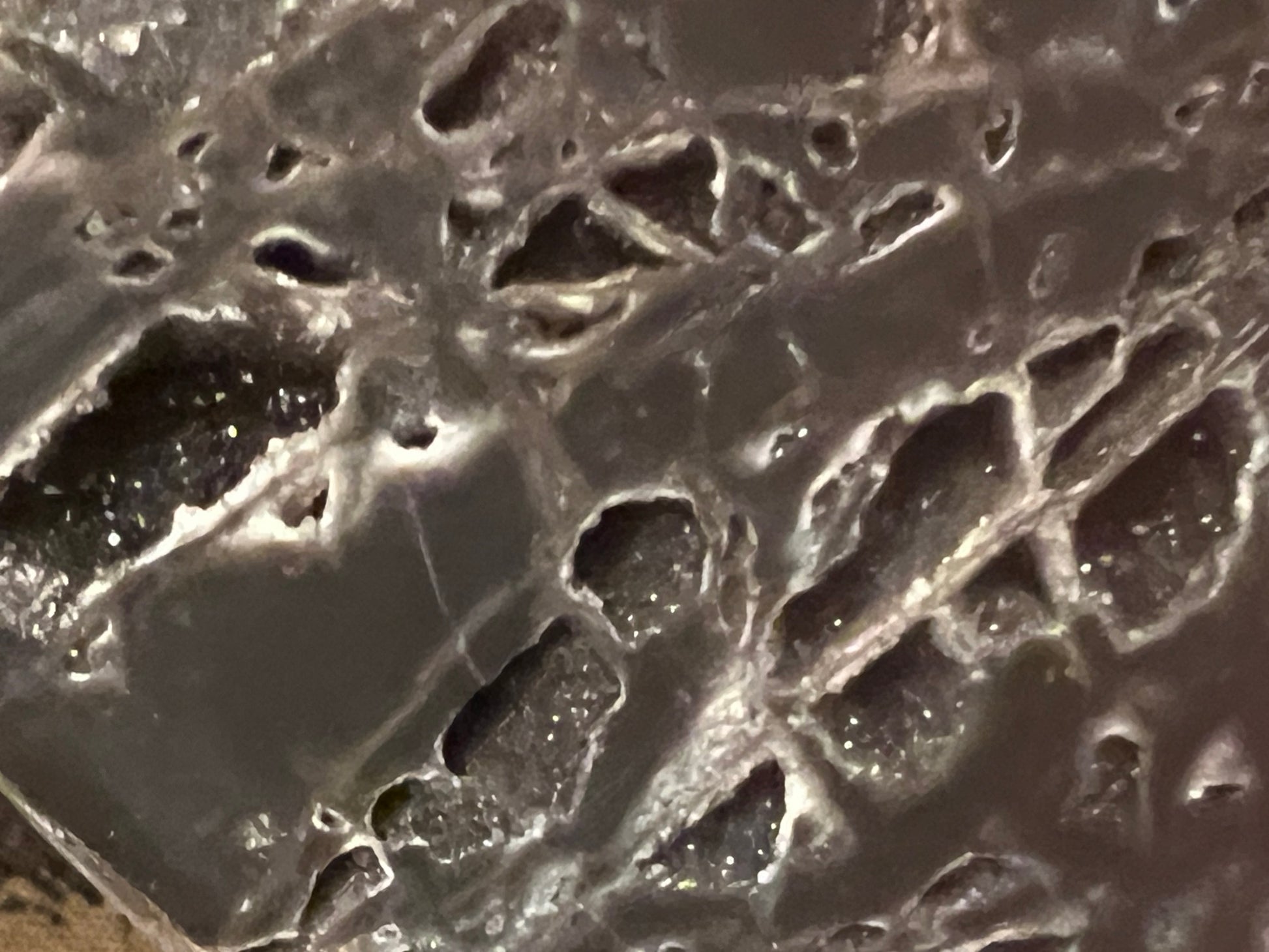 Geode with dark gray exterior and white, crystal-filled pockets.