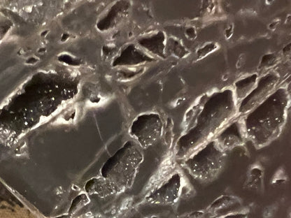 Geode with dark gray exterior and white, crystal-filled pockets.
