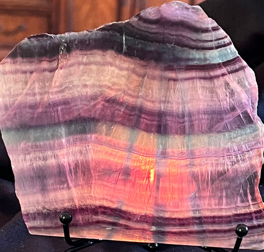 Polished slab of purple and grey banded fluorite on a display stand.