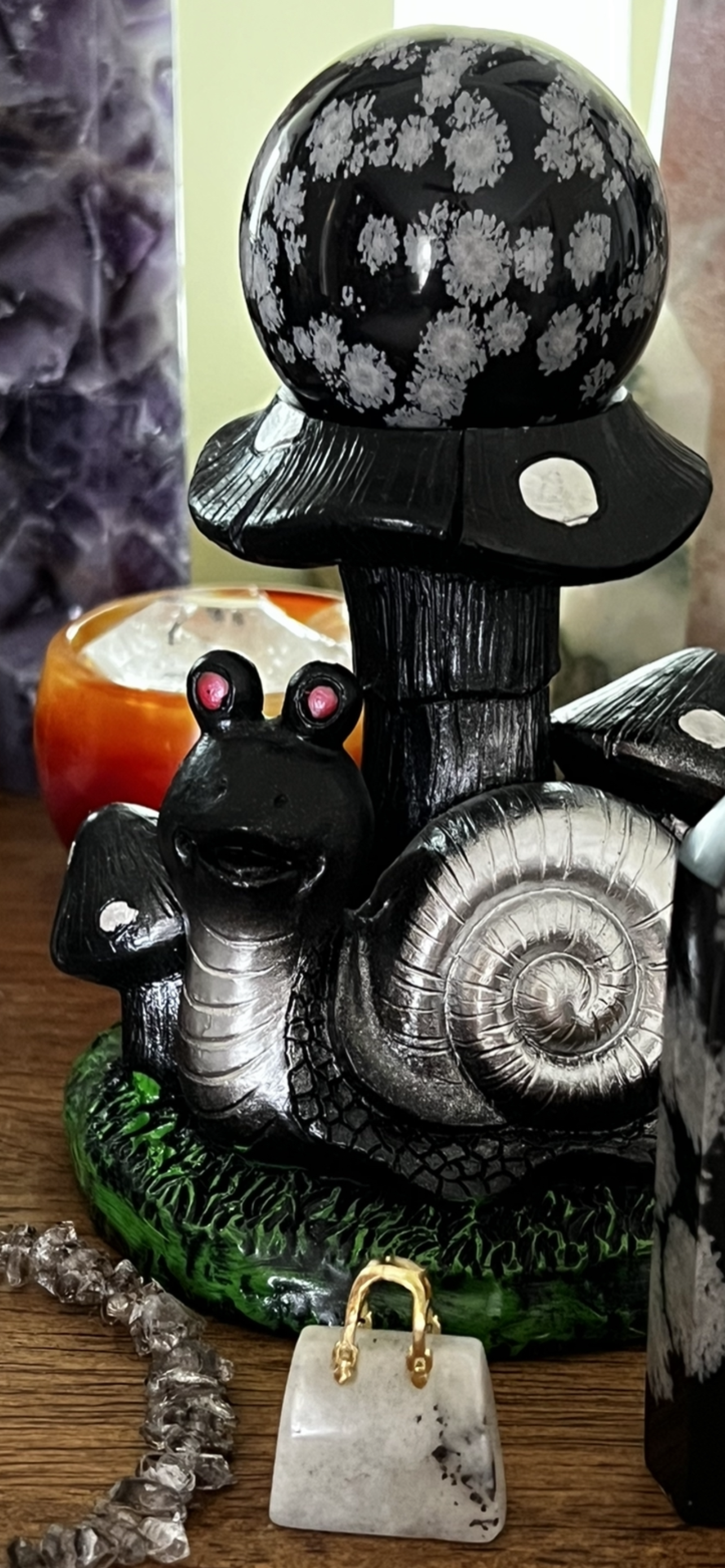 Snail figurine with mushroom cap and snowflake obsidian sphere.
