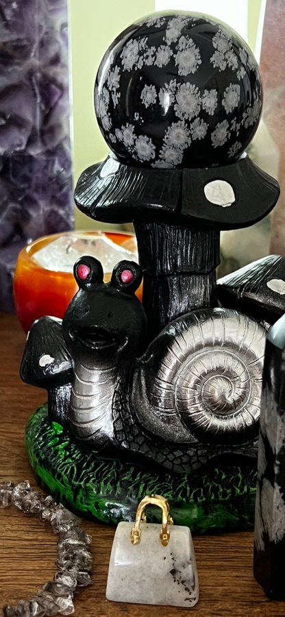 Snail figurine with mushroom cap and snowflake obsidian sphere.
