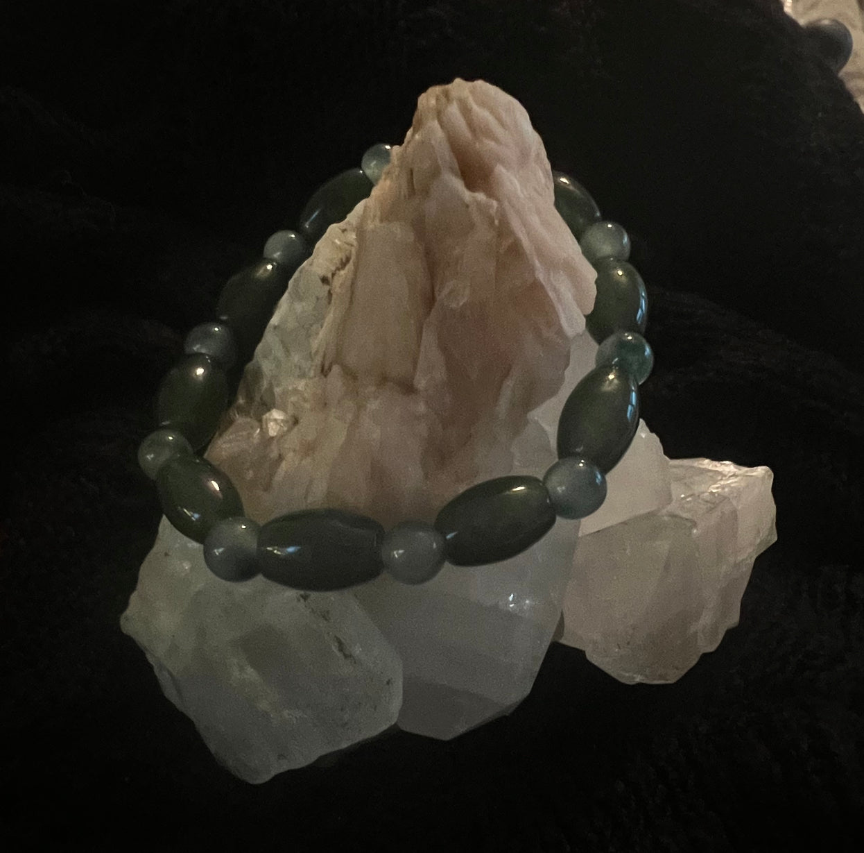 A beaded bracelet is draped over several white crystals.