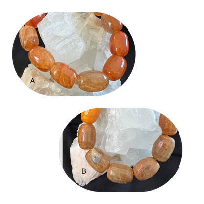 Two bracelets made of polished, orange-brown stones. A rests atop white crystals, while B is below.
