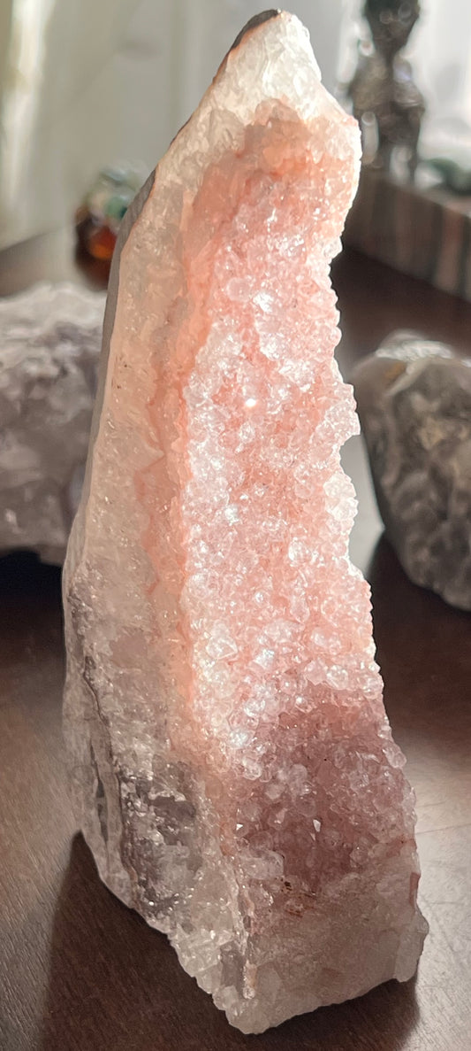 A pink and clear crystal geode on a brown surface.