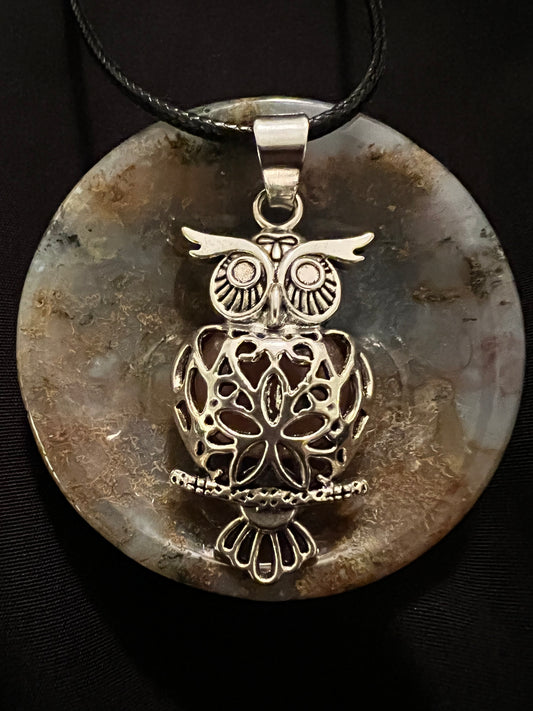 Owl pendant on stone disk with black cord.